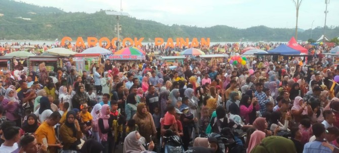 RAMAI: Pengunjung di pelataran parkir Kawasan Wisata Pantai Carocok Painan terlihat membludak, dan foto pengunjung saat berendam di pinggir pantai Pulau Cingkuak di kawasan itu.(IST)