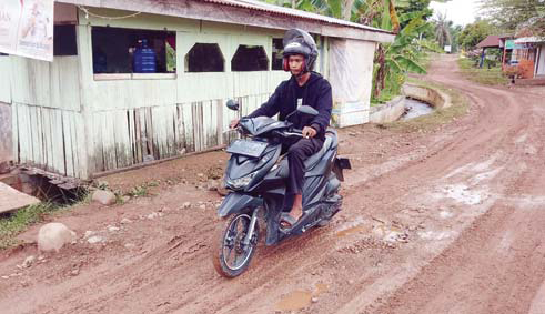 BUTUH PERHATIAN: Salah seorang pengendara sepeda motor melintasi jalan yang licin di Jalan Simpang Akhirat, Kecamatan Kuranji Padang, kemarin.(YOLLA FITRIA/PADEK)