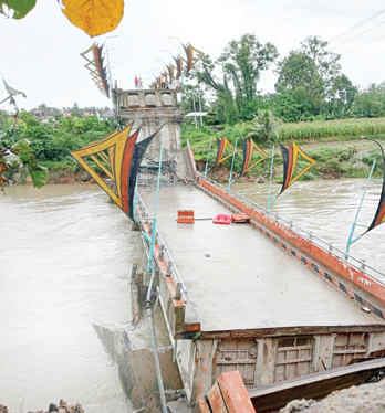 AMBRUK: Kondisi Jembatan Kayu Gadang di Kecamatan Lubukalung, Kabupaten Padangpariaman, kemarin. Sebagian badannya terban ke dalam sungai pada Minggu malam (7/5) lalu.(ARIS PRIMA G/PADEK)