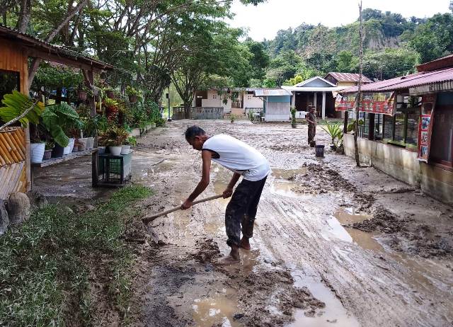 Pemilik warung lesehan sedang membersihkan lumpur akibat luapan Sungai Ngarai Sianok, Selasa (9/5). RIAN AFDOL/PADEK