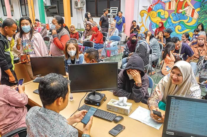SAMPAIKAN ADUAN: Sejumlah orang tua siswa mendatangi posko PPDB di kantor Dinas Pendidikan Surabaya, Jumat (23/6). Pemakaian sistem dua zonasi dikeluhkan banyak warga. (Dipta Wahyu/Jawa Pos)