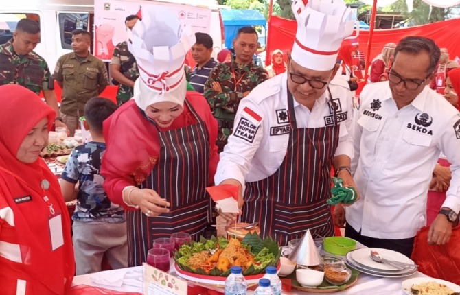 Bupati Solok Epyardi Asda dan istri Ny Emiko disaksikan Sekkab Medison mengikuti lomba memasak nasi goreng di kawasan Dermaga Singkarak, Selasa (15/8/2023).
