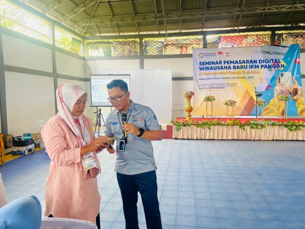 Pinca BRI Painan, Alvin Nur Muhammad, saat mengenalkan aplikasi BRI kepada salah seorang peserta seminar.(IST)