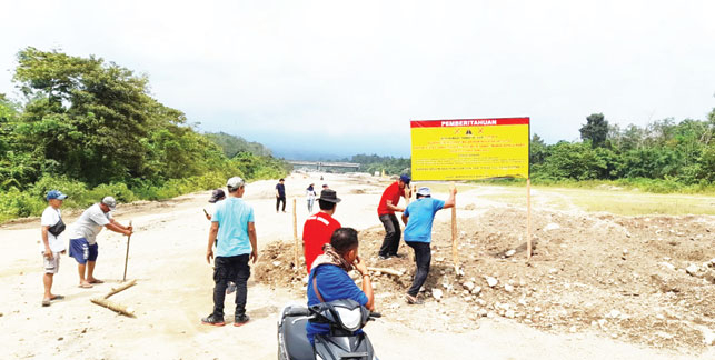 MENGGUGAT: Pihak Hanafi Cs saat pemasangan plang peringatan di atas tanah mereka, pekan lalu. Kondisi tersebut membuat akses menuju titik pengerjaan tol di Tarok terblokir.(DOK HANAFI CS)