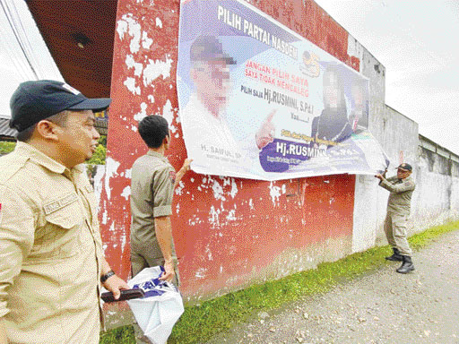 MELANGGAR: Petugas gabungan mencopot APS yang melanggar di kawasan Tanjuangpati, Kabupaten Limapuluh Kota, kemarin (21/11).(BAWASLU LIMAPULUH KOTA FOR PADEK)
