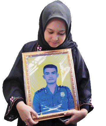 KORBAN ERUPSI: Salah seorang kakak Bripda Muhammad Iqbal membawa foto almarhum usai pulang dari upacara pemakaman di TPU Tunggulhitam, Kecamatan Kototangah, Padang, Rabu (6/12).(ADETIO/PADEK)