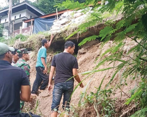 RUSAK PARAH : Petugas mengecek satu unit rumah yang tertimpa longsor Sabtu, kemarin. Selain itu dua unit rumah juga terban di Jorong Mudiakliki, Nagari Kurai, Kecamatan Suliki, Limapuluh Kota.(BENI EKA PUTRA FOR PADEK)