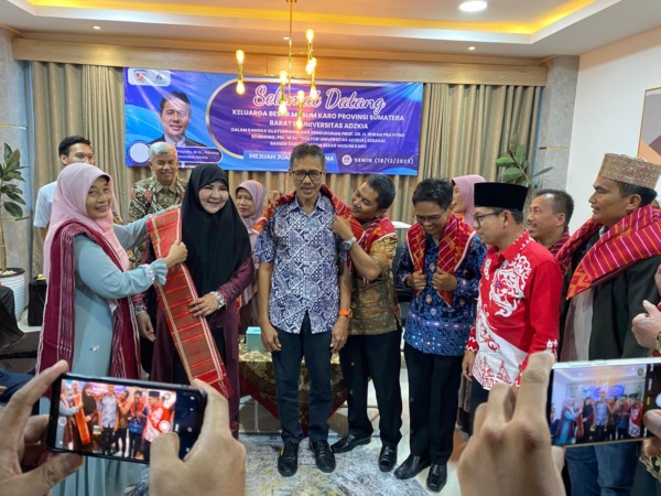 KEHORMATAN: Rektor Universitas Adzkia Prof Irwan Prayitno dipasangkan kain beka buluh pertanda resmi menyandang marga Sembiring dari suku Karo. Sang istri, Hj Nevi Zuairina menyandang marga Boru Sitepu. (dok.pribadi)