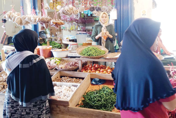 LAYANI PEMBELI: Salah seorang pedagang sembako di Pasar Raya Padang sedang melayani pembeli, Selasa (12/12).(SHYNTIA/PADEK)