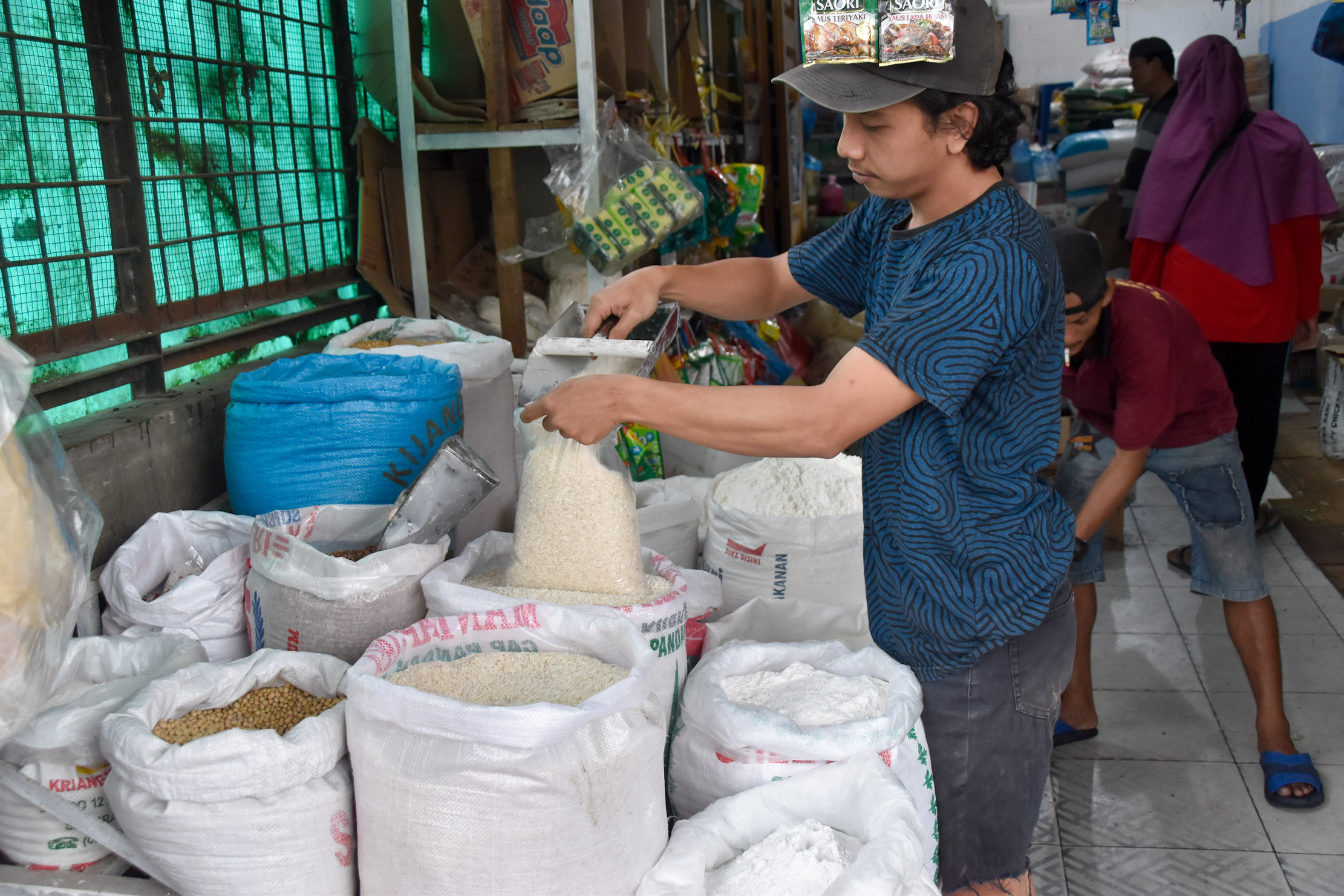 AMBIL BERAS: Seorang pedagang sedang mengambil beras dagangannya untuk ditimbang di Pasar Simpanglimun, Jalan M Nawi Harahap Medan, belum lama ini.