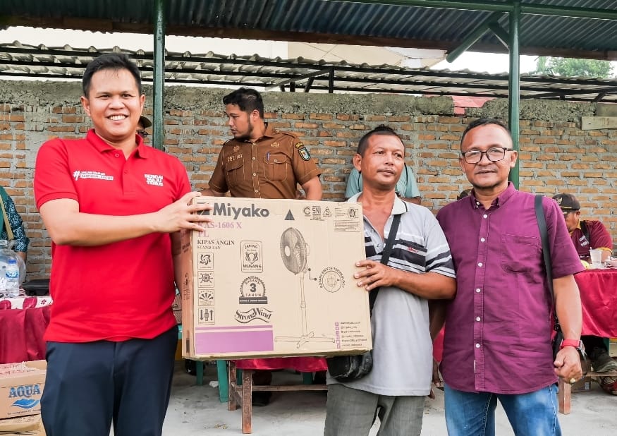 SERAHKAN: Wabup Sergai H. Adlin Tambunan menyerahkan hadiah lucky draw berupa kipas angin kepada Yanto pedagang sempol.  ( Fad )