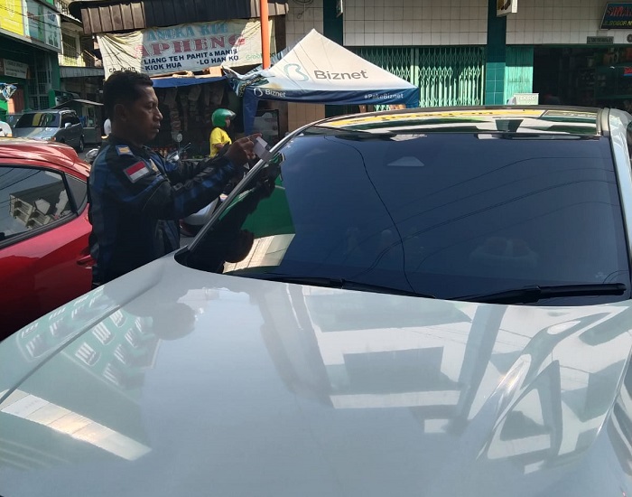 TEMPEL: Petugas Dinas Perhubungan Kota Medan menempel stiker parkir berlangganan kepada  kendaraan masyarakat.