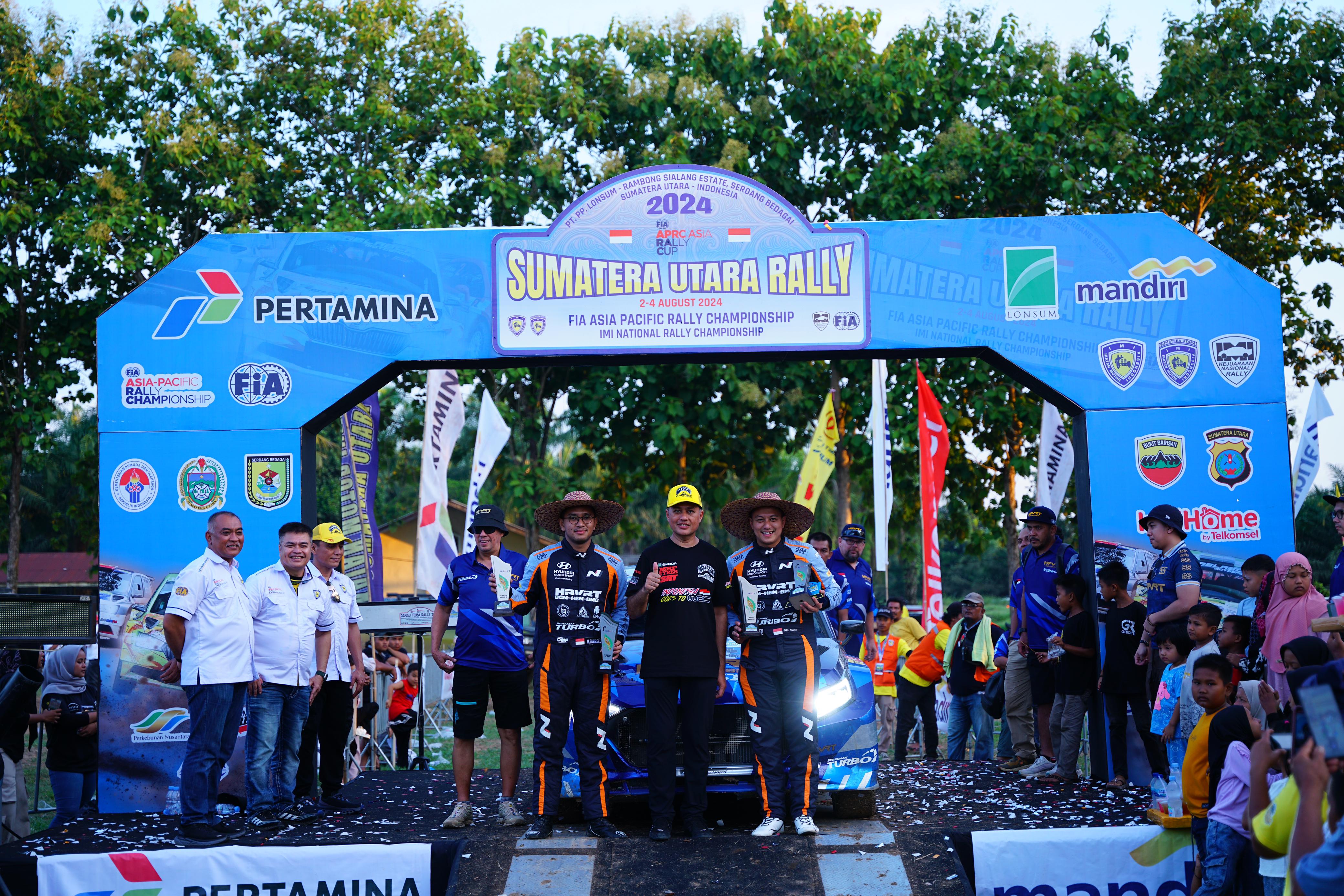 PODIUM: Juara Sumatera Utara Rally Rihans Variza dan co-driver M Fahreza Fahd, naik podium juara di Lapangan Bola Gaharap, Rambong Sialang, Sergai, Minggu (4/8/2024). (IMI Sumut)