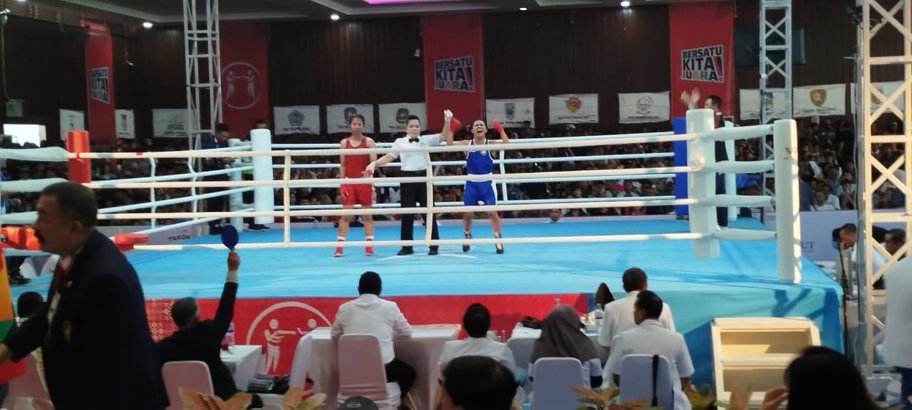 MENANG: Wasit mengangkat tangan petinju dari sudut biru sebagai pemenang  usai mengalahkan petinju sudut merah pada duel final PON XXI 2024. FOTO : FAJAR/SUMUT POS