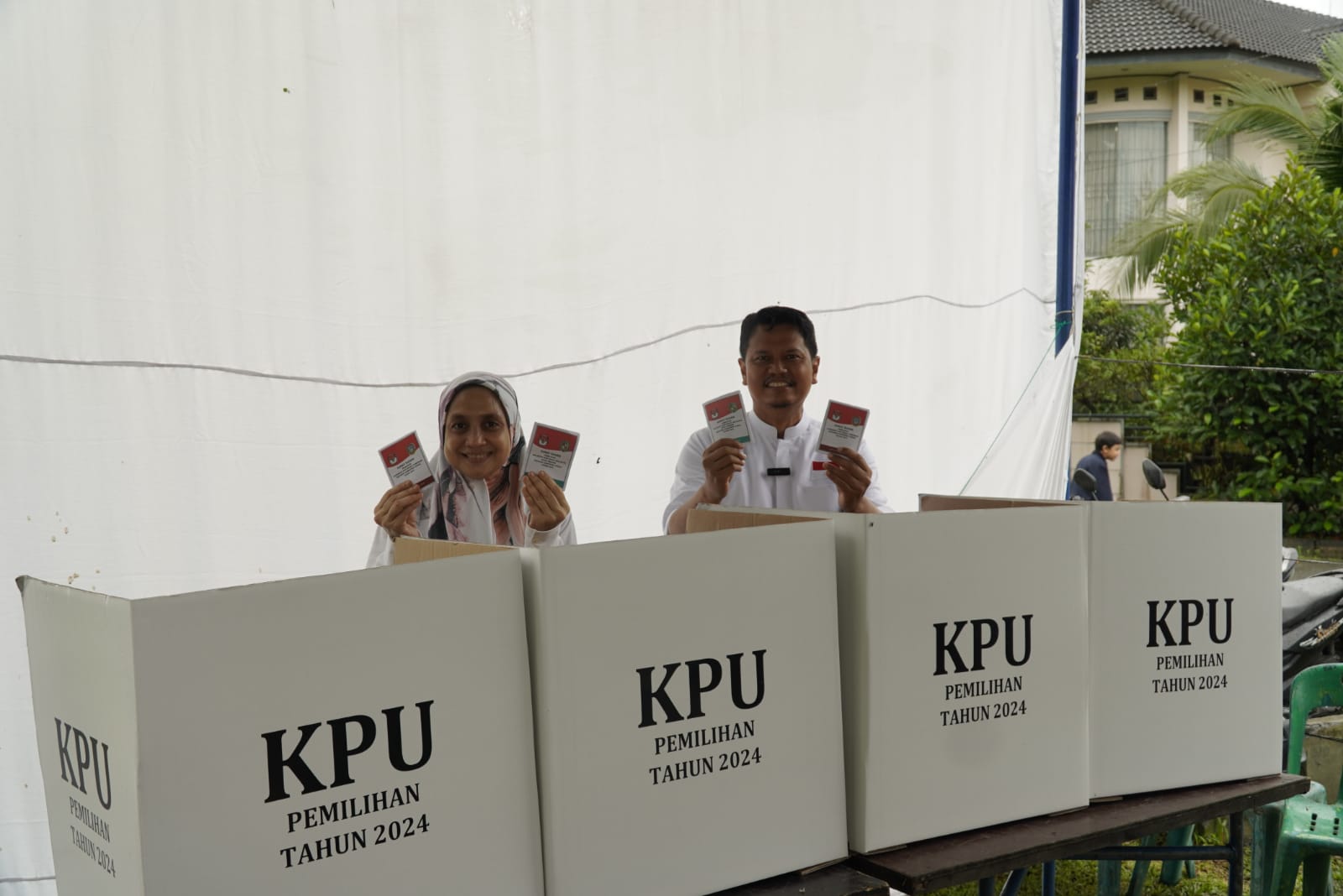 SURAT SUARA: Calon Wali Kota Medan nomor urut 2, Prof Ridha Dharmajaya bersama istri menunjukkan surat surat mereka usai mencoblos di TPS 23 Komplek Tasbih 2, Rabu (27/11/2024) pagi. (MARKUS PASARIBU)