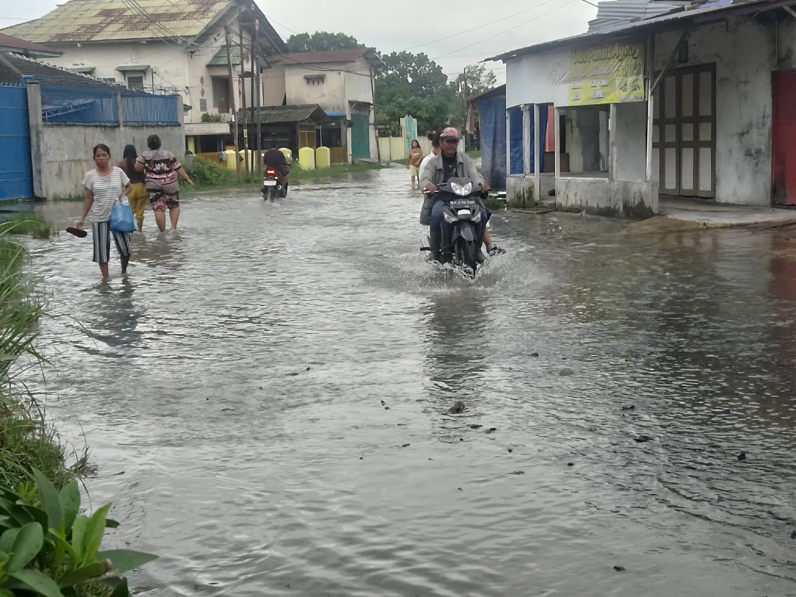 BANJIR: Pengendara sepedamotor Kewalahan melintasi genangan air  yang sudah memasuki pemukiman penduduk. FOTO: IKHSAN/SUMUT POS