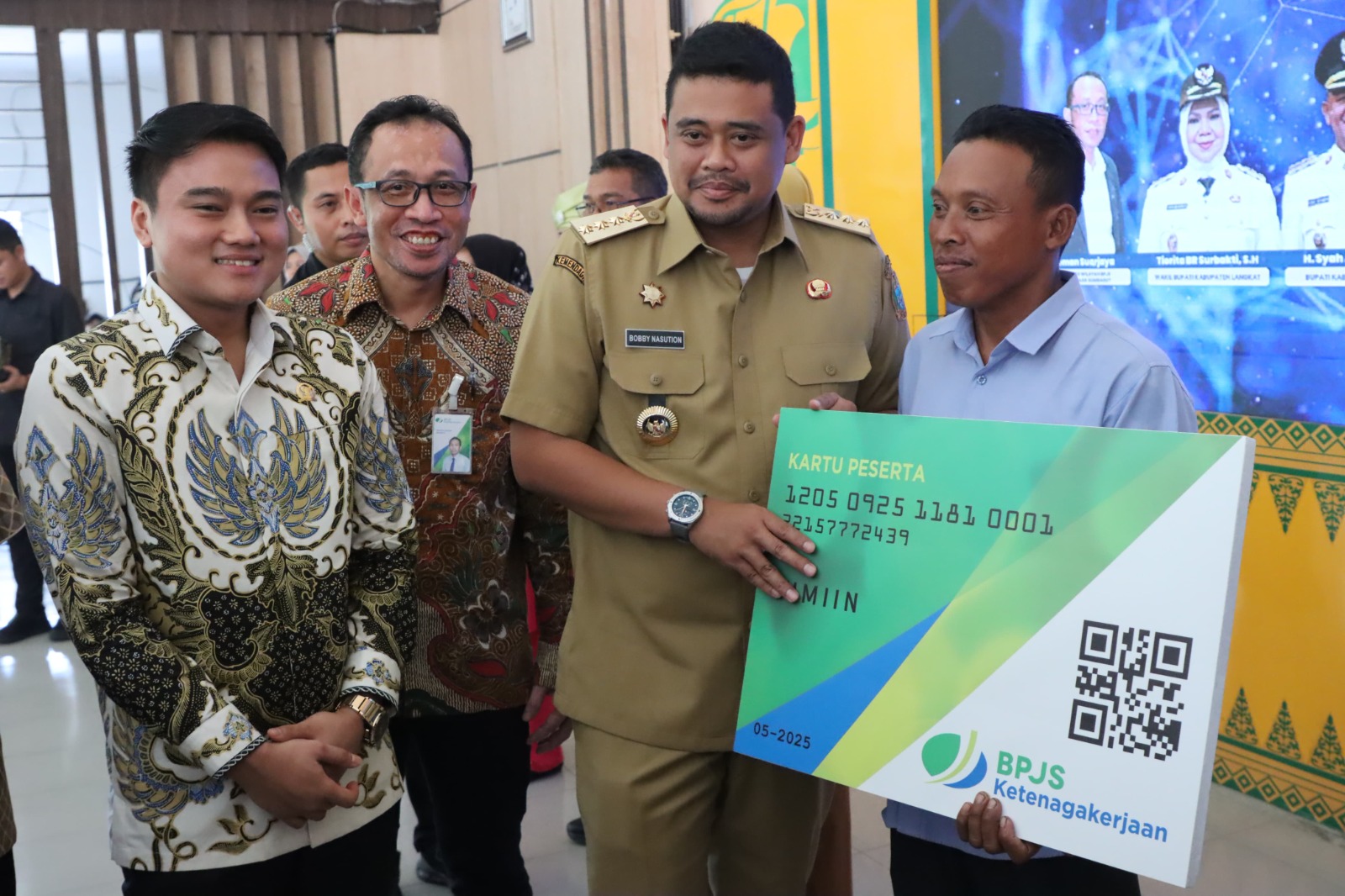 SERAHKAN: Pimpinan DPRD Sumut, Ricky Anthony (kiri) saat mendampingi Gubsu Bobby menyerahkan kartu kepesertaan BPJS Ketenagakerjaan secara simbolis di Stabat. Istimewa/Sumut Pos