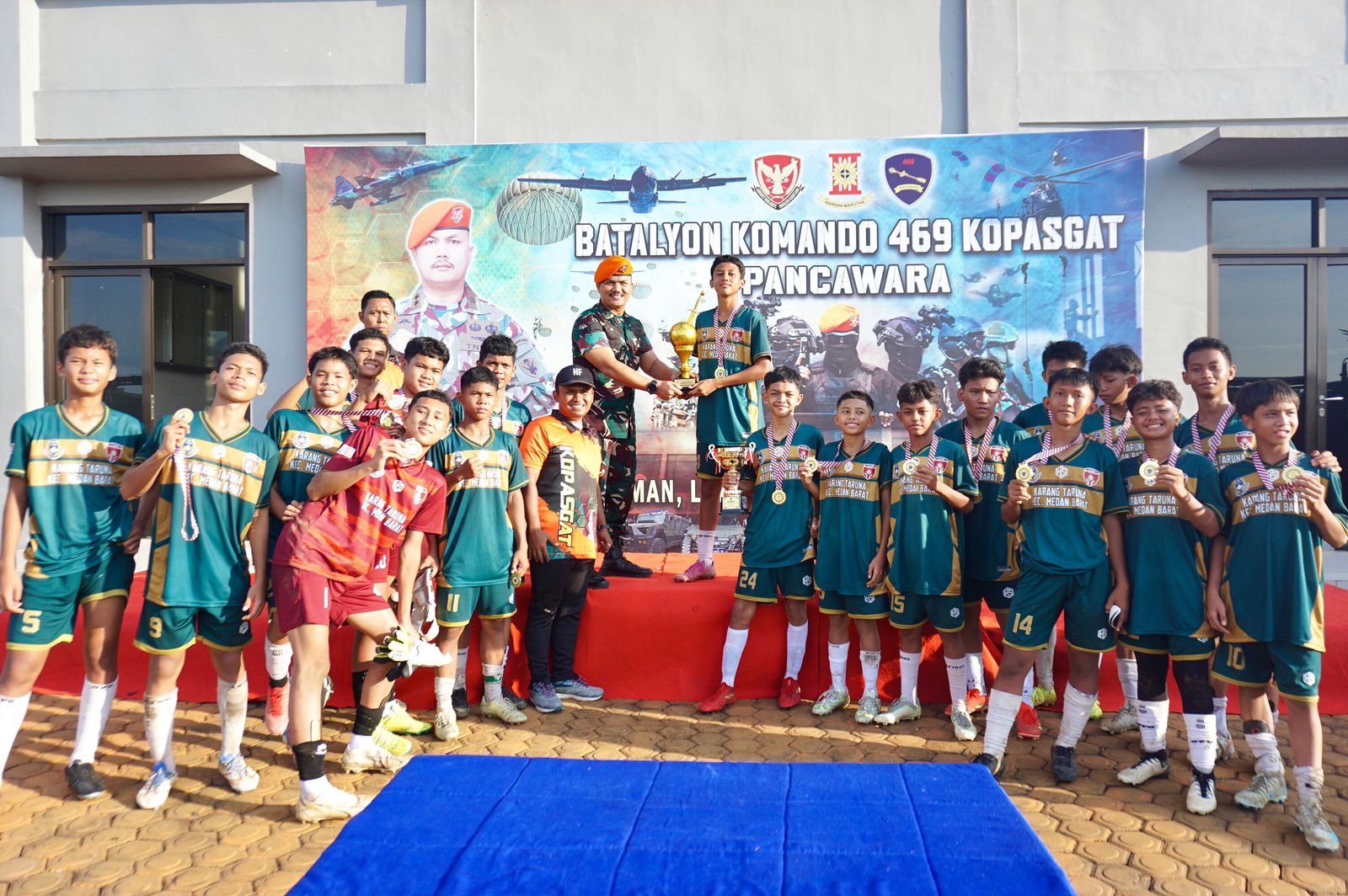 JUARA: Danyonko 469 Kopasgat, Letkol Pas Jhon Herriansyah Siregar menyerahkan piala juara I kepada SSB TGM, Minggu (8/6) foto: ISTIMEWA/SUMUT POS