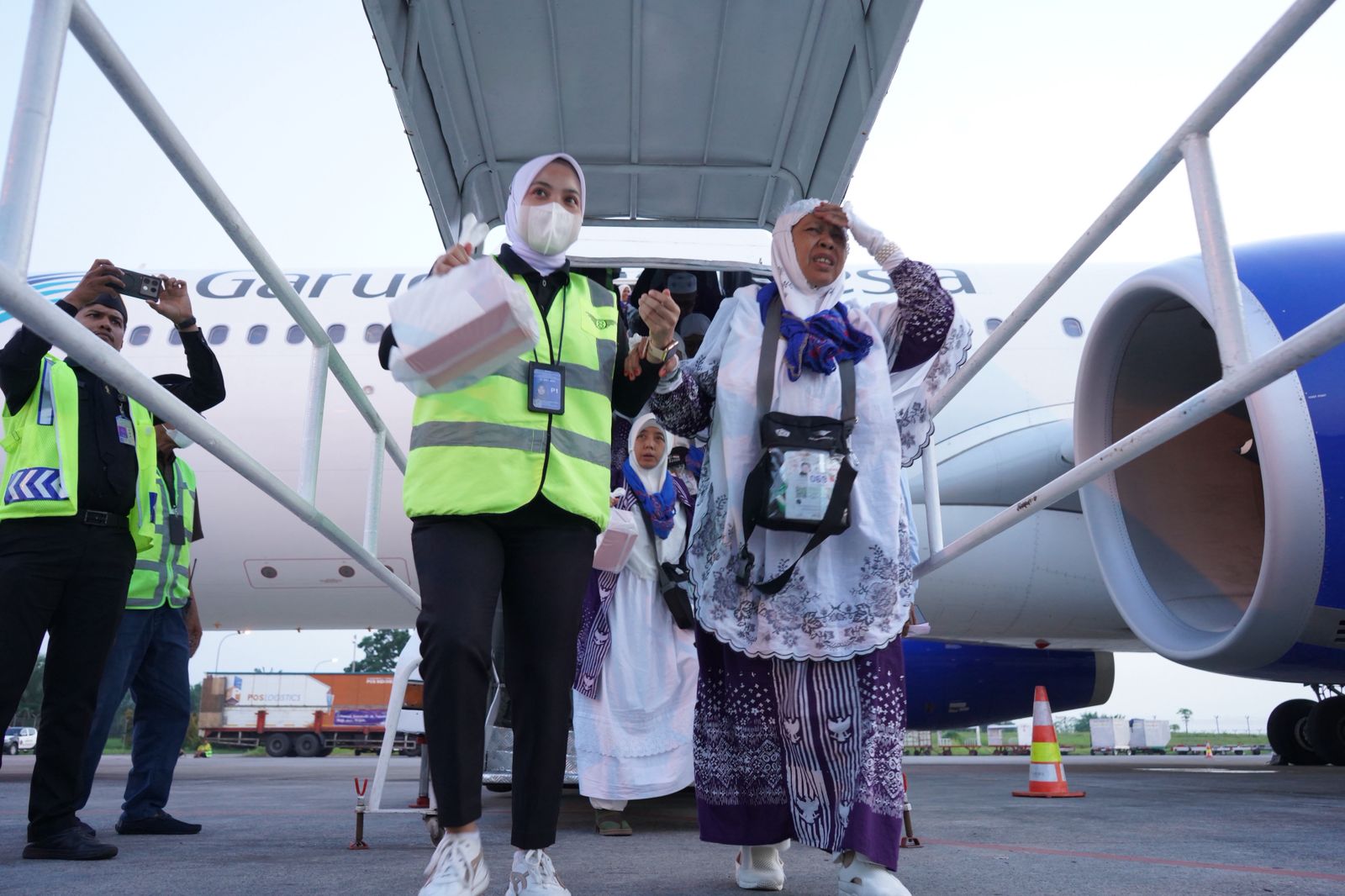 DITUNTUN: Seorang petugas haji menuntun salah seorang jamaah haji Kloter 20 saat turun dari pesawat, Sabtu(5/7) sore.