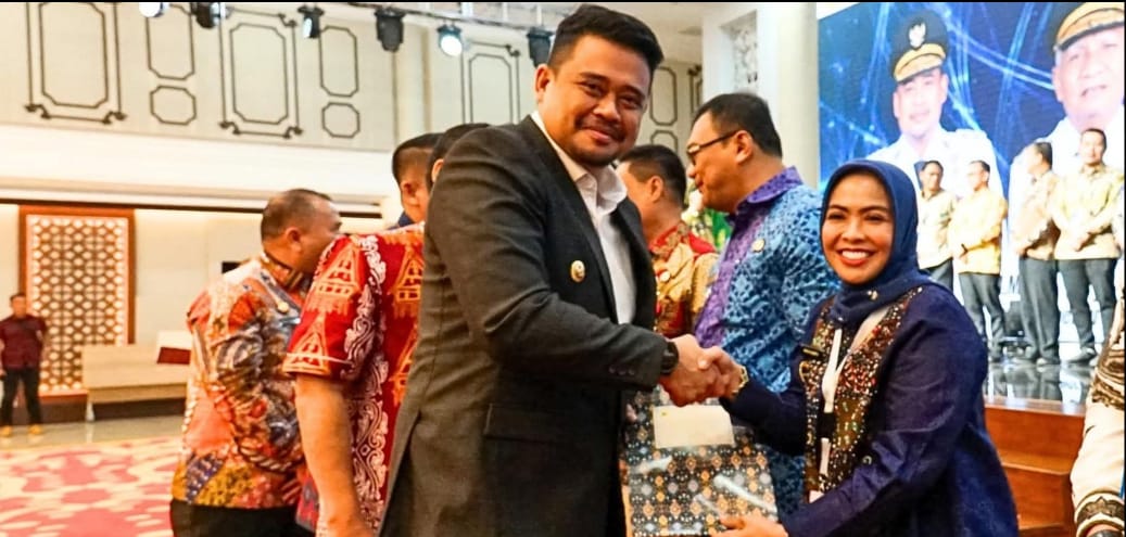 SALAM: Bupati Labuhanbatu, Maya Hasmita bersalaman dengan Gubsu, Bobby Nasution saat penyerahan DBH di Medan, Jumat (8/8/2025). (Dok: Diskominfo Labuhanbatu)