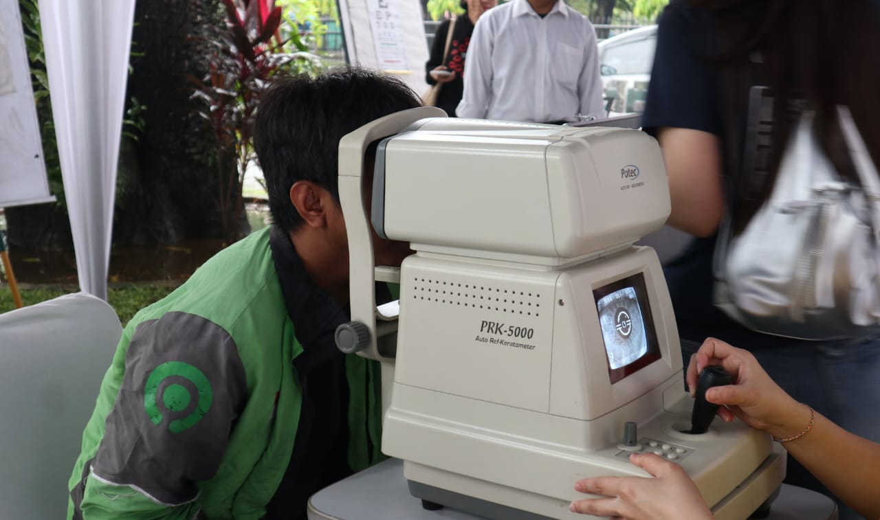 Petugas kesehatan memeriksa mata para Ojol dan keluarga dengan alat komputer yang di fasilitasi Bank Mestika.
