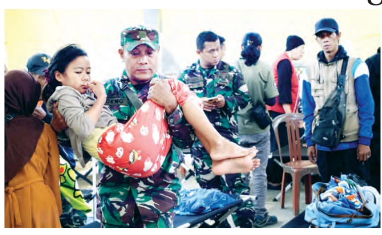 Personel TNI sedang membopong seorang anak yang mengalami keracunan makanan usai menyantap menu MBG.