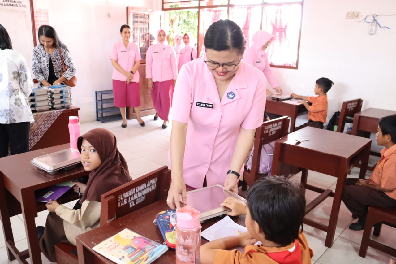Ketua Kemala Bhayangkari Polres Labuhanbatu,  Rina Choky memberikan makanan MBG ke salah seorang siswa di yayasan tersebut. (FAJAR/SUMUT POS)