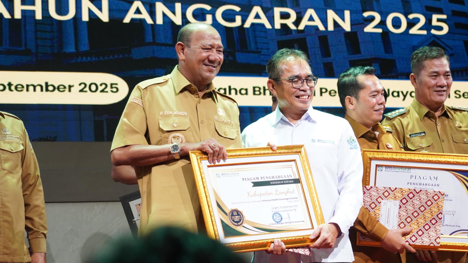 Bupati Langkat, Syah Afandin (kiri) menerima penghargaan UHC. (Diskominfo Langkat/Sumut Pos)