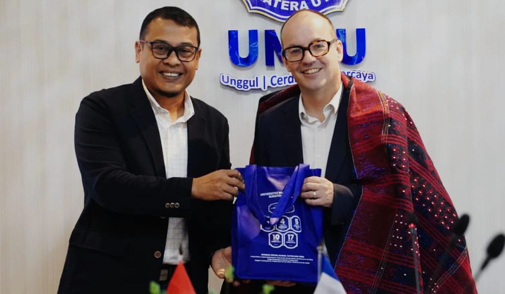 TERIMA ULOS: Dr Rudianto MSi (kiri) memakaikan ulos dan menyerahkan cendera mata kepada Antoine Bricout. (ISTIMEWA/SUMUT POS)