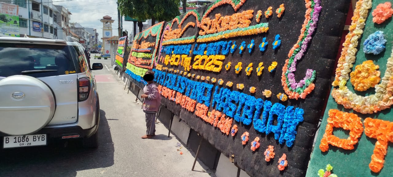Seorang anak jalanan mengais rezeki dari pengendara di kawasan simpang empat, Rantauprapat berlatar papan bunga perayaan HUT ke-80 Pemkab Labuhanbatu (FAJAR/SUMUT POS)