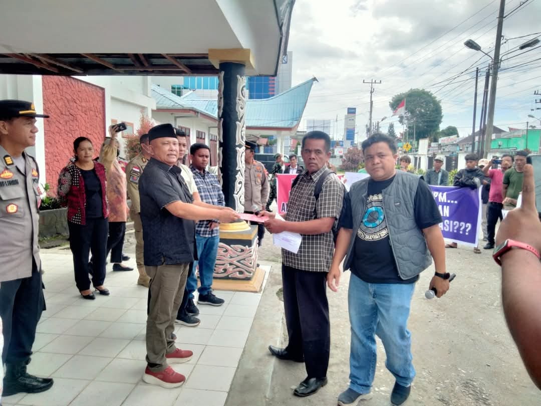 SERAHKAN. Orator aksi, Oberlin Tua Pasaribu dan Bernad Malau menyerahkan tuntutan kepada Ketua DPRD Dairi, Sabam Sibarani saat aksi di Kantor DPRD Dairi, Kamis (23/10/2025).(RUDY SITANGGANG/SUMUT POS)