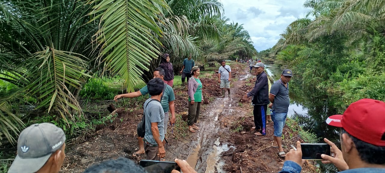 PARIT: Warga menunjukkan jalan yang becek dan berlumpur dampak pengerukan parit yang dilakukan Perkebunan Adipati PT SMART di Labura. (Dok: Fajar Dame/Sumut Pos)