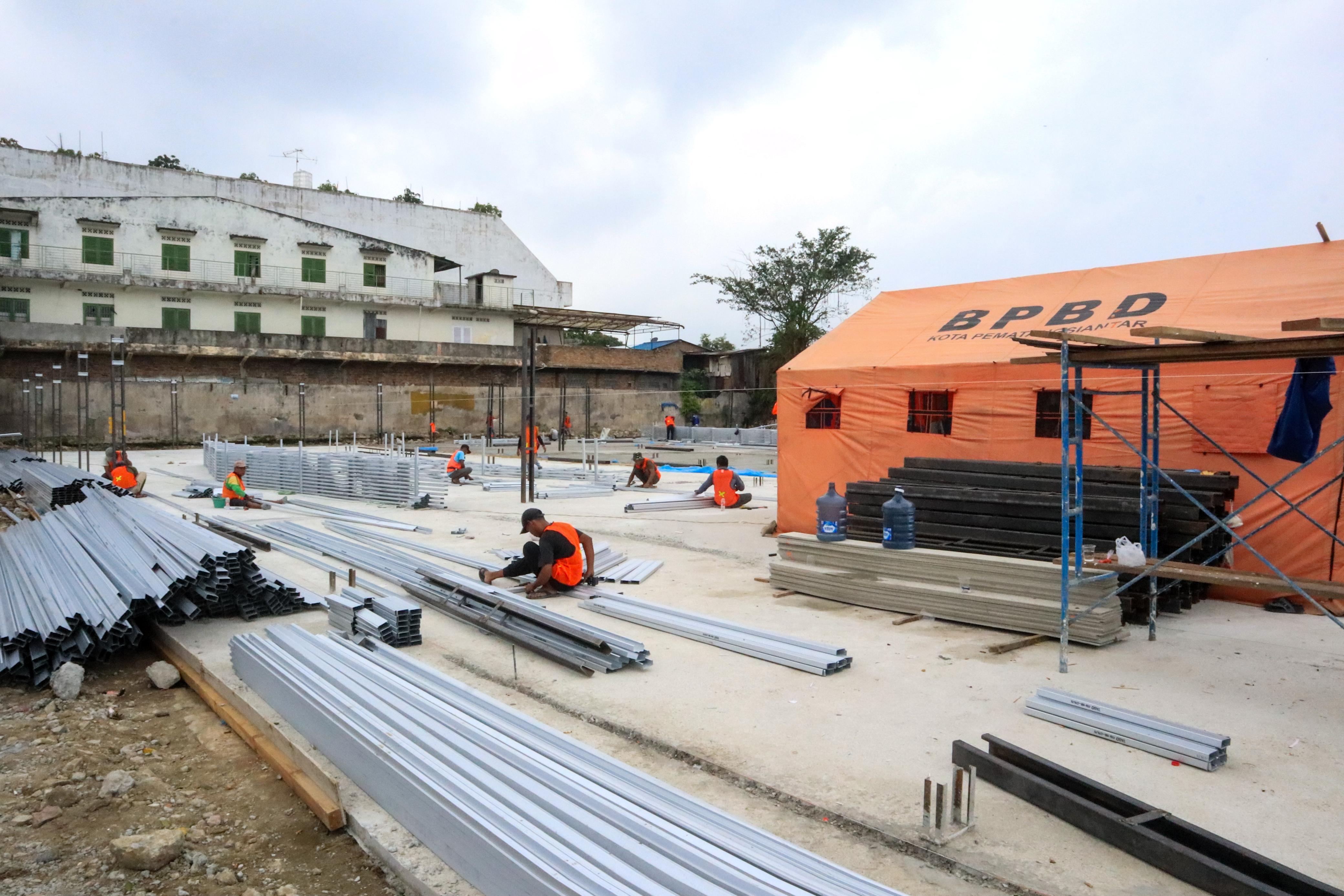 Sejumlah pekerja sedang mempersiapkan kios darurat di lahan gedung pasar horas yang telah dirobohkan. (PRA EVASI/SUMUT POS)