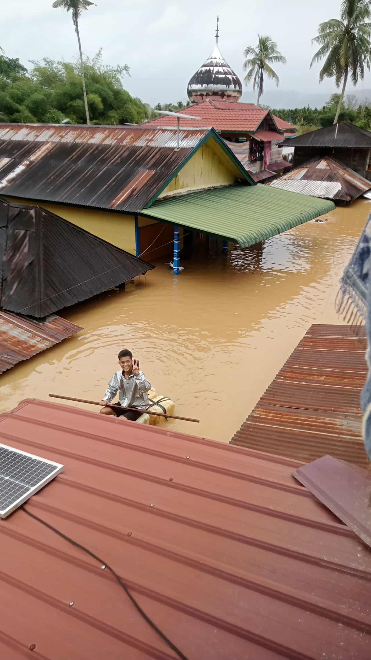 Seorang warga terpaksa menggunakan sampan buatan untuk mengevakuasi warga karena rumah terendam banjir. (SUBANTA RAMPANG AYU/SUMUT POS)