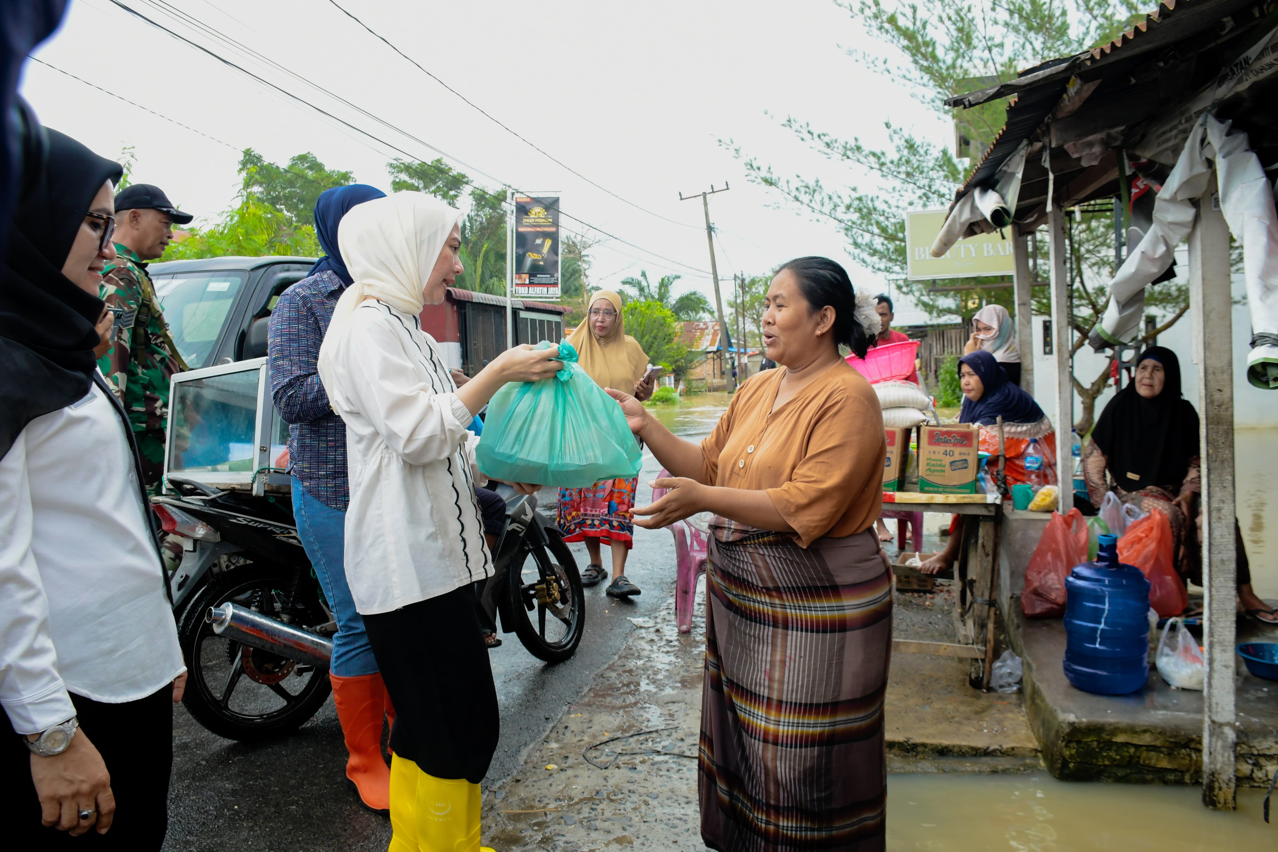 Ketua GOPTKI Sergai Ny. Aini Zetara Adlin Tambunan menyerahkan bantuan makanan kepada warga terdampak banjir di Kecamatan Tanjung Beringin.( Fadly/Sumut Pos )