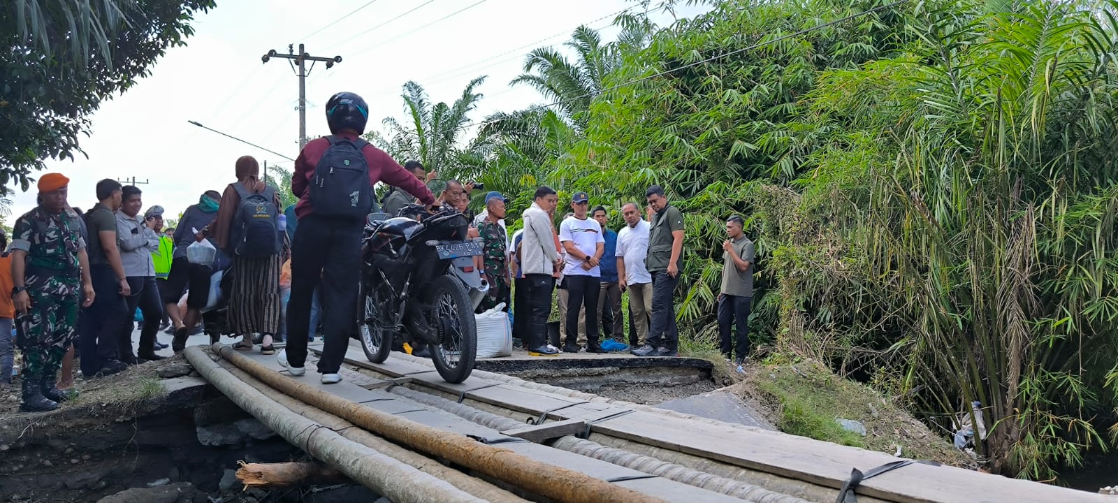 Pengendara motor saat mendorong kendaraannya melintas di Jalan Utama Padangtualang-Batangserangan yang terputus. (Teddy Akbari/Sumut Pos)