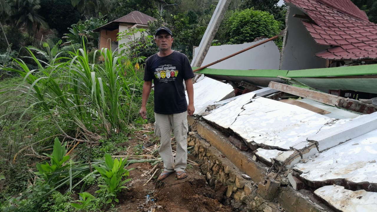 AMBLAS: Seorang warga melihat rumah amblas akibat adanya pergeseran tanah. (SUBANTA RAMPANG AYU/SUMUT POS)
