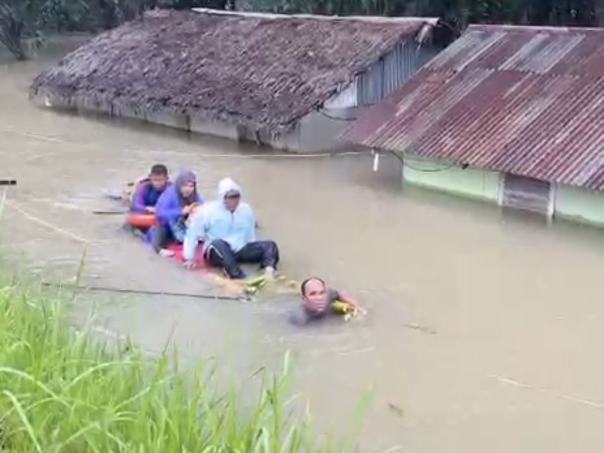 Istimewa/Sumut Pos Kapolsek Pangkalanbrandan, AKP Amrizal Hasibuan saat evakuasi masyarakat korban banjir dengan rakitan batang pohon pisang. (ISTIMEWA/SUMUT POS)