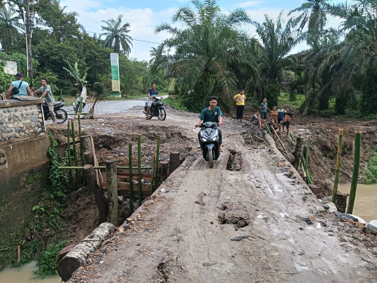 AMBLAS: Warga saat melintasi titi darurat Tambak Kulim penghubung antar desa yang amblas karena tergerus waktu. (Dok: Indra Lubis/SUMUT POS)