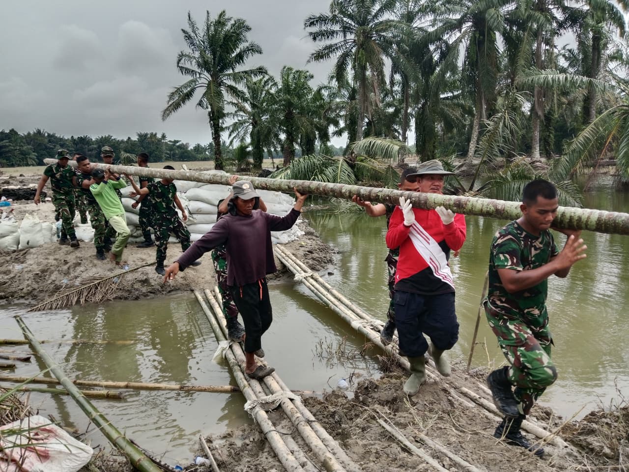 Prajurit TNI saat memperbaiki tanggul yang jebol di Langkat. (Sumut Pos/Dokumen Pribadi)