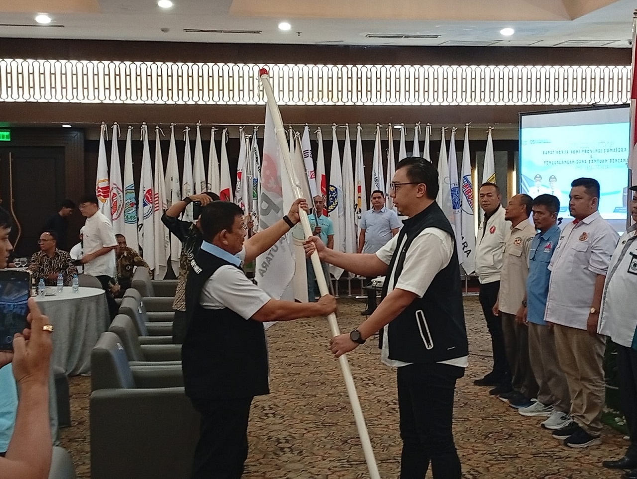 TERIMA PATAKA: Ketua Umum KONI Sumut Kol (purn) Hatunggal Siregar menerima pataka dari cabang olahraga baru pada Reker KONI Sumut di Hotel Emerald Garden, Selasa (16/12/2025). (Dok Pribadi)