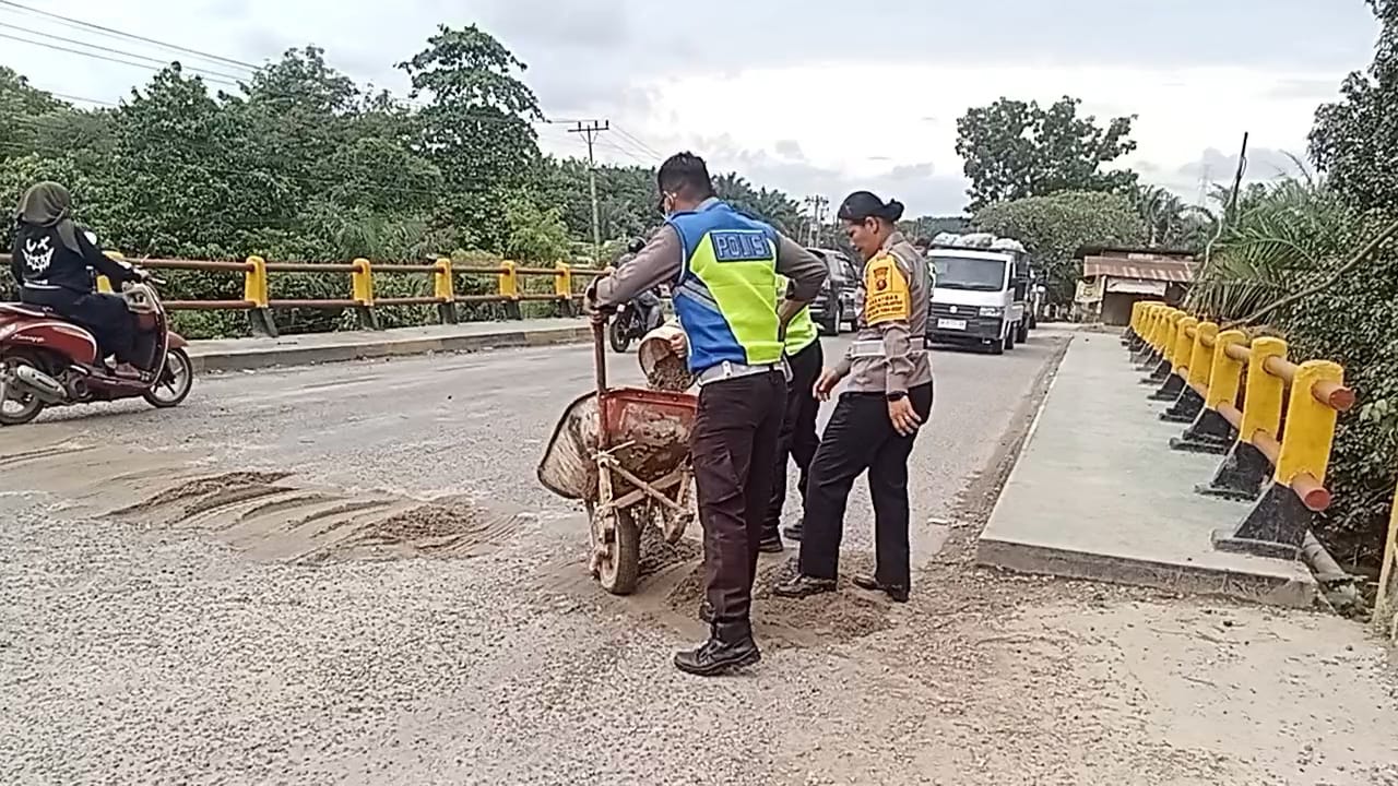 TIMBUN: Personel Polres Labuhanbatu Selatan sedang menimbun Jalinsum Bedagai demi kenyamanan pengendara. (Dok: istimewa)