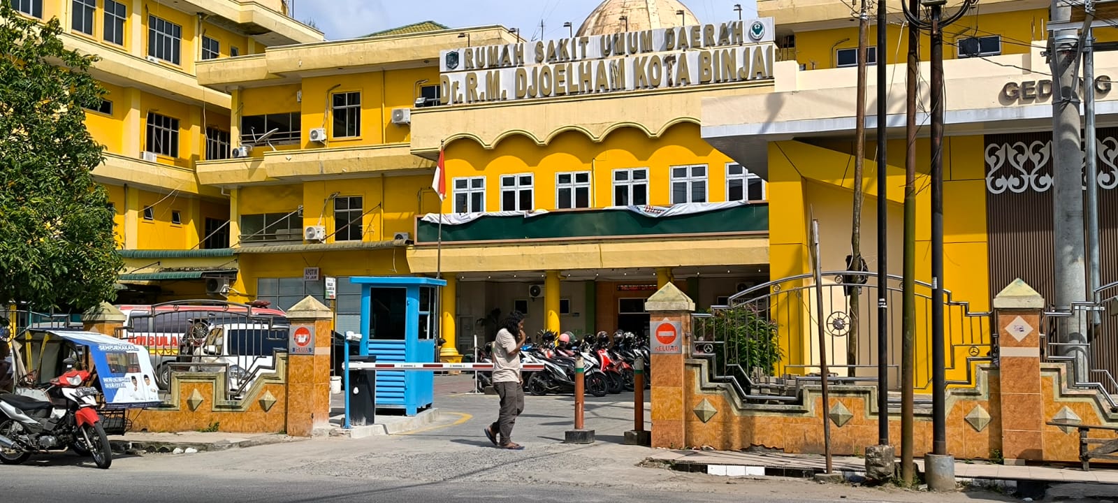 DEPAN: Seorang pria berjalan di depan portal parkir berbayar pada RSUD Djoelham Binjai. (Dok: Teddy Akbari/Sumut Pos)
