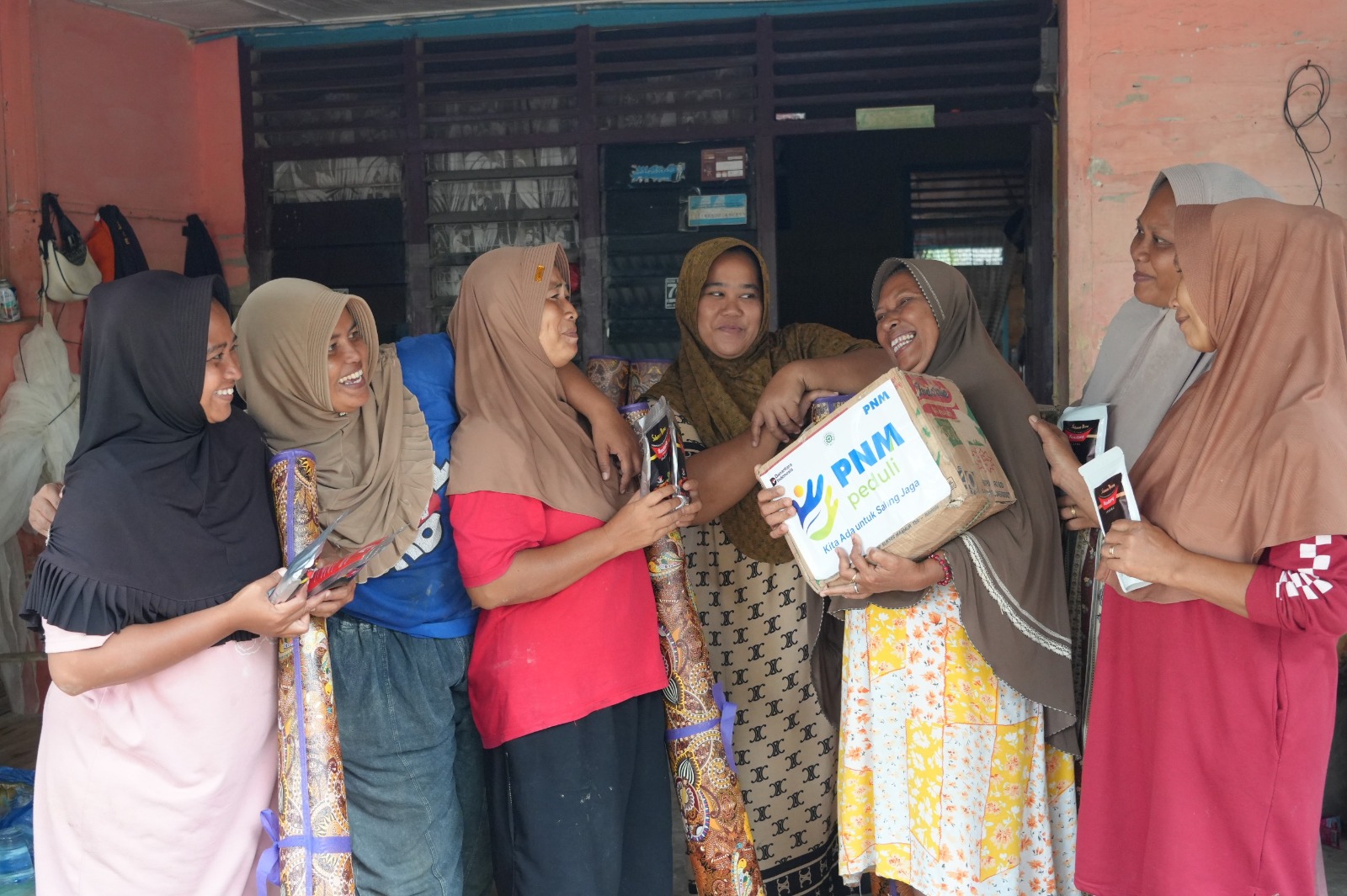 GEMBIRA: Nasabah PNM Mekaar yang terdampak bencana Sumatera saat menerima bantuan berupa abon dan daging rendang. (Dok: PNM)