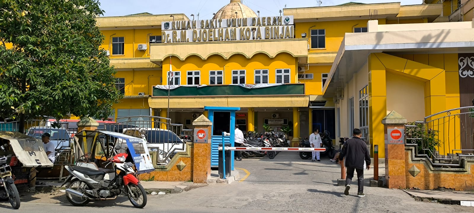 Seorang pria saat melintas di depan portal parkir berbayar pada RSUD Djoelham, Jalan Sultan Hasanuddin. (Teddy Akbari/Sumut Pos)