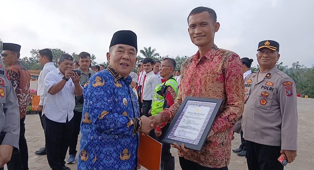 Wakil Bupati Syahdian Purba Siboro SH memberikan penghargaan kepada Dedi Irwanto di halaman Mapolres Labuhanbatu Selatan. (KHAIRUDDIN/SUMUT POS)