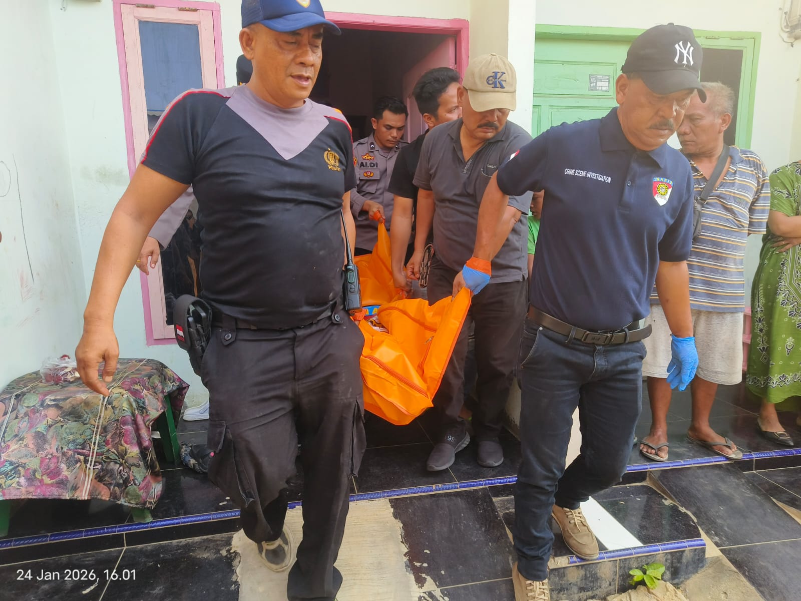 ANGKAT: Personel Polisi saat mengangkan jenazah di TKP yang ditemukan dalam keadaan tergantung di balik pintu kamar yang terkunci (24/1/2026). (Dok: istimewa)