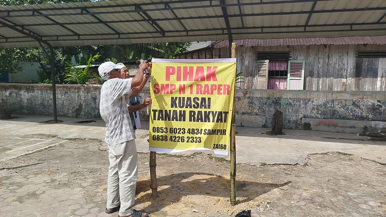 SPANDUK: Ahli Waris Djiwo Kromo memasangi spanduk di komplek SMPN 1 Rantau Utara (Dok: Fajar/Sumut Pos)