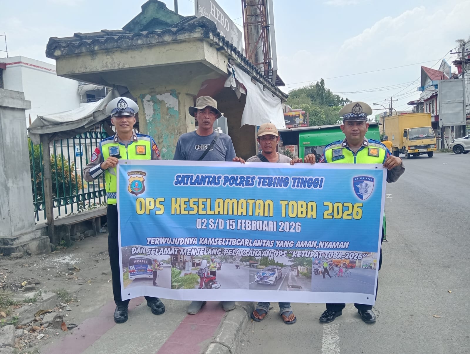 Personel Satlantas Polres Tebing Tinggi bersama masyarakat membentangkan spanduk Ops Keselamatan Toba 2026 saat kegiatan Dikmas di jalan raya.