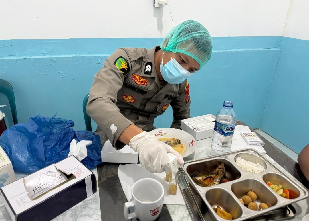 CEK: Seorang personel Polres labusel mengecek porsi MBG sebelum dibagikan kepada para pelajar di Kota Pinang untuk disantap. (KHAIRUDDIN/SUMUT POS(